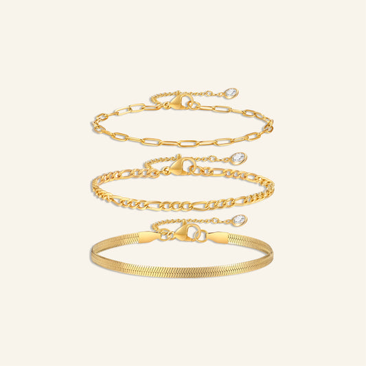 3-pack armband i guldpläterat rostfritt stål: papperslänk, pansarkedja och ormkedja, med justerbara avslut och cubic zirconia-detalj.